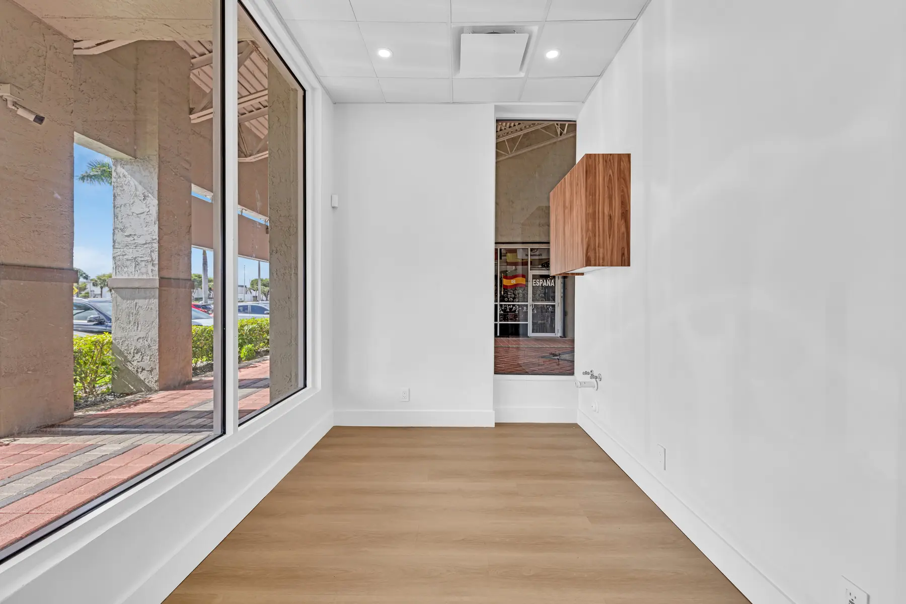 Empty suite with a large window, interior window and walnut wall cabinet