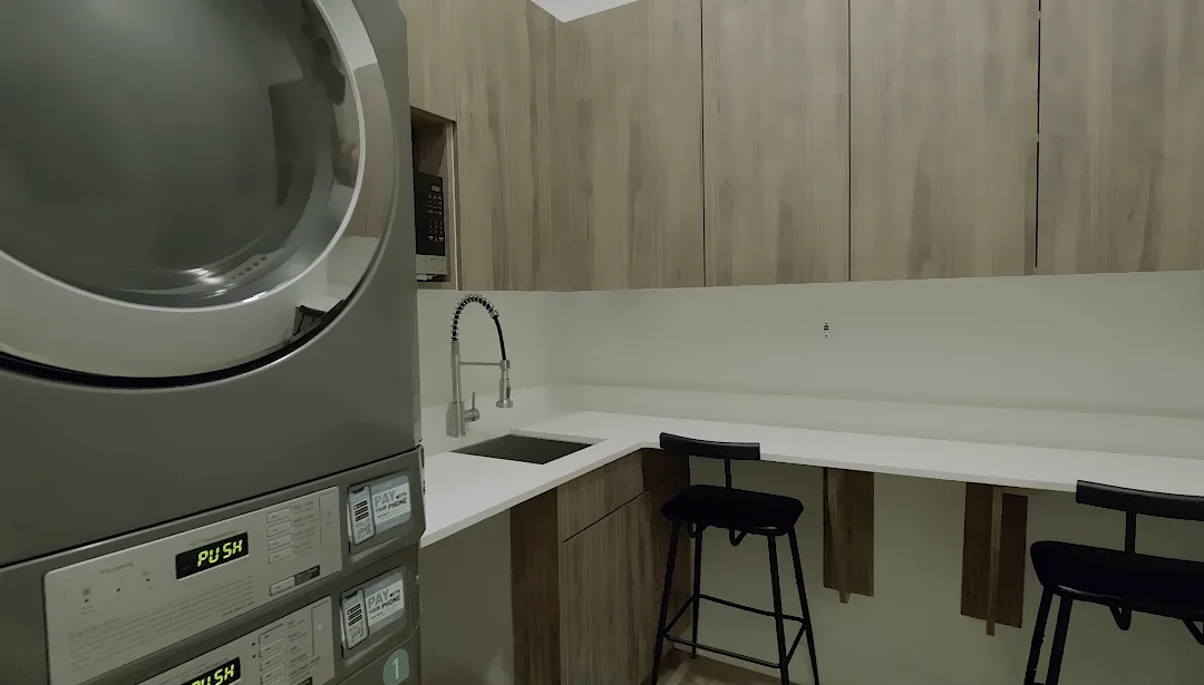 Laundry room with stacked washer and dryer, sink and bar stools