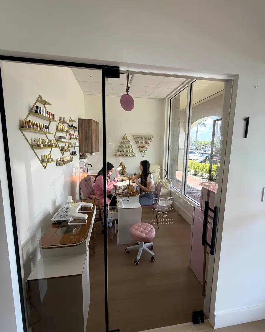 Nail studio in suite 1 with gold shelves, a pink chair and two clients at the manicure table
